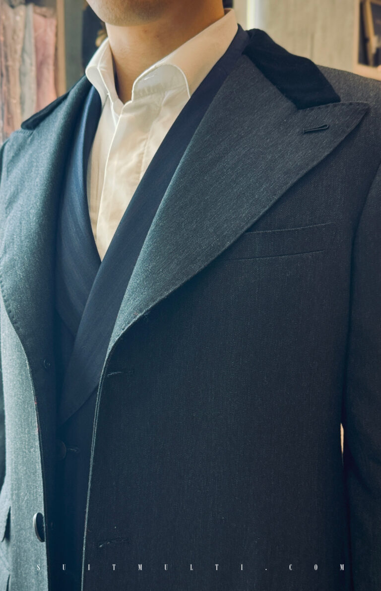 peaky-blinders-style-bespoke-overcoat-velvet-lapel,一件深炭灰色羊毛大衣的領口特寫，展示了寬大的劍領與對比色的黑色絲絨上領片。